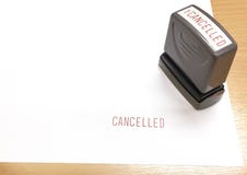 Le texte rouge, CANCELLED a été embouti avec le tampon en caoutchouc sur le livre blanc image stock Le texte rouge, CANCELLED a été embouti avec le tampon en caoutchouc sur le livre blanc image stock