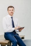 Le tir vertical de l'homme d'affaires sérieux utilise la tablette moderne pour des actualités financières de lecture en ligne, fa photographie stock Le tir vertical de l'homme d'affaires sérieux utilise la tablette moderne pour des actualités financières de lecture en ligne, fa photographie stock