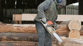 Le travailleur de la construction coupe la tronçonneuse en bois pour la future maison Masque protecteur et écouteurs sur la tête banque de vidéos Le travailleur de la construction coupe la tronçonneuse en bois pour la future maison Masque protecteur et écouteurs sur la tête banque de vidéos