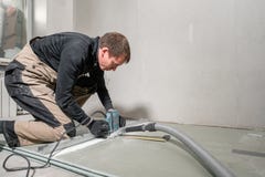 Le travailleur emploie un outil de construction, les outils de fraisage et un aspirateur cloison sèche à quatre-vingt-dix degrés images stock Le travailleur emploie un outil de construction, les outils de fraisage et un aspirateur cloison sèche à quatre-vingt-dix degrés images stock