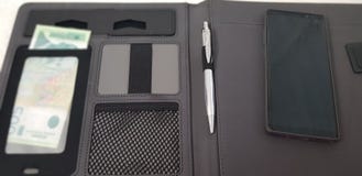 Le téléphone intelligent s'étendent sur le dossier en cuir ouvert avec un stylo et une monnaie fiduciaire serbe photo libre de droits Le téléphone intelligent s'étendent sur le dossier en cuir ouvert avec un stylo et une monnaie fiduciaire serbe photo libre de droits