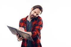 Le téléphone parlant d'homme triste et écrit dans le carnet image stock Le téléphone parlant d'homme triste et écrit dans le carnet image stock