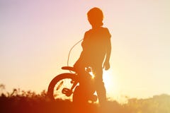 Le vélo d'équitation de petit garçon au coucher du soleil, enfants folâtrent photos stock Le vélo d'équitation de petit garçon au coucher du soleil, enfants folâtrent photos stock