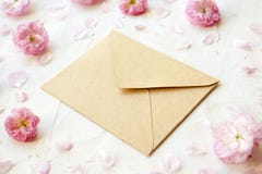 Leerer geschlossener Kraftpapierumschlag für Mutter ` s Tag mit Kopienraum für Text unter rosa blühenden Blüten auf weißem Hinter stockfotos Leerer geschlossener Kraftpapierumschlag für Mutter ` s Tag mit Kopienraum für Text unter rosa blühenden Blüten auf weißem Hinter stockfotos