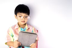 Leest de Nerdy Aziatische jongen op tablet stock afbeelding Leest de Nerdy Aziatische jongen op tablet stock afbeelding