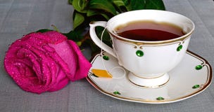 Legen Sie auf dem Tisch eine Rose und nahe bei einer Porzellan Schale mit Tee stehen lizenzfreies stockfoto Legen Sie auf dem Tisch eine Rose und nahe bei einer Porzellan Schale mit Tee stehen lizenzfreies stockfoto