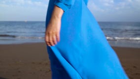 Legs of a woman in beautiful blue dress walking along a black volcanic beach stock video footage Legs of a woman in beautiful blue dress walking along a black volcanic beach stock video footage