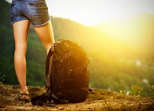 Legs of a woman tourist and travel backpack on a mountain top