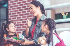 Lehrerlesegeschichtenbuch zu den Kindergartenstudenten greifen oben ab lizenzfreies stockbild Lehrerlesegeschichtenbuch zu den Kindergartenstudenten greifen oben ab lizenzfreies stockbild