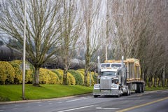 Leistungsfähiger klassischer amerikanischer großer der Anlage LKW halb, der halb Handelsfracht auf dem Anhänger des Flachbetts fä lizenzfreie stockbilder Leistungsfähiger klassischer amerikanischer großer der Anlage LKW halb, der halb Handelsfracht auf dem Anhänger des Flachbetts fä lizenzfreie stockbilder