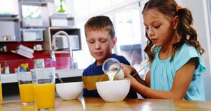 Leite de derramamento da menina na bacia de cereal na cozinha video estoque Leite de derramamento da menina na bacia de cereal na cozinha video estoque