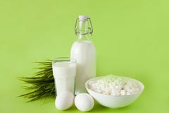 Leite em um requeijão dos ovos da garrafa e em um vidro do leite em um fundo verde com grama imagens de stock Leite em um requeijão dos ovos da garrafa e em um vidro do leite em um fundo verde com grama imagens de stock
