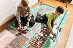 Lek för två pojkar med robotar som de skapade från den robotic konstruktörn på det färgrika banret på golvet i royaltyfri bild Lek för två pojkar med robotar som de skapade från den robotic konstruktörn på det färgrika banret på golvet i royaltyfri bild