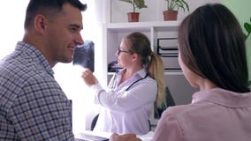 Lekarka z dobre'em wieści utrzymuje promieniowanie rentgenowskie w jego ręce i mówi o zdrowie młoda para w klinice płodności zbiory wideo Lekarka z dobre'em wieści utrzymuje promieniowanie rentgenowskie w jego ręce i mówi o zdrowie młoda para w klinice płodności zbiory wideo