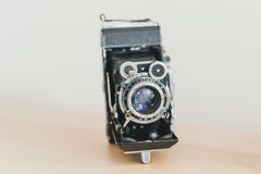 lensharmonika op een oude camera Oude uitstekende camera op een houten lichte achtergrond royalty-vrije stock afbeelding lensharmonika op een oude camera Oude uitstekende camera op een houten lichte achtergrond royalty-vrije stock afbeelding