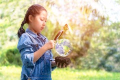 Lente d'ingrandimento asiatica della tenuta della ragazza che trova le piante di crescita nel mondo verde immagini stock libere da diritti Lente d'ingrandimento asiatica della tenuta della ragazza che trova le piante di crescita nel mondo verde immagini stock libere da diritti