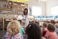 Leraar At Montessori School die aan Kinderen in Verhaaltijd lezen royalty-vrije stock fotografie Leraar At Montessori School die aan Kinderen in Verhaaltijd lezen royalty-vrije stock fotografie