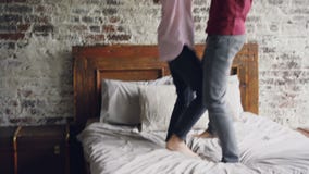 Les amants heureux dansent sur le lit tenant des mains et appréciant la vie mariée ensemble Double lit moderne, mur de briques et banque de vidéos Les amants heureux dansent sur le lit tenant des mains et appréciant la vie mariée ensemble Double lit moderne, mur de briques et banque de vidéos
