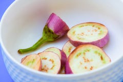 Les aubergines de brinjal découpent des morceaux en tranches sur le backg bleu d'isolement par tasse blanche photographie stock Les aubergines de brinjal découpent des morceaux en tranches sur le backg bleu d'isolement par tasse blanche photographie stock