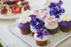 Les beaux petits gâteaux faits maison avec le massepain pourpre, blanc et rose fleurit sur le dessus photos libres de droits Les beaux petits gâteaux faits maison avec le massepain pourpre, blanc et rose fleurit sur le dessus photos libres de droits