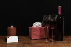 Les beaux verres de vin et bouteille gravés à l'eau-forte de vin rouge, bougie rouge, ont enveloppé actuel avec l'arc sur la tabl images stock Les beaux verres de vin et bouteille gravés à l'eau-forte de vin rouge, bougie rouge, ont enveloppé actuel avec l'arc sur la tabl images stock