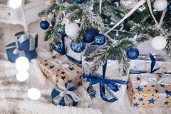 Les cadeaux de Noël enveloppés en papier argenté et bleu, fond avec Noël allume le bokeh de brouiller sous l'arbre de Noël image libre de droits Les cadeaux de Noël enveloppés en papier argenté et bleu, fond avec Noël allume le bokeh de brouiller sous l'arbre de Noël image libre de droits