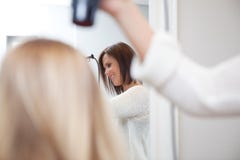 Les cheveux de la femme de séchage de styliste photo stock Les cheveux de la femme de séchage de styliste photo stock