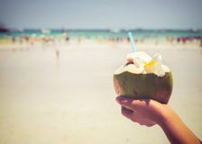 Les cocktails frais de noix de coco avec chez des mains de la femme sur la plage tropicale - vacation en été Photographie stock Les cocktails frais de noix de coco avec chez des mains de la femme sur la plage tropicale - vacation en été Photographie stock