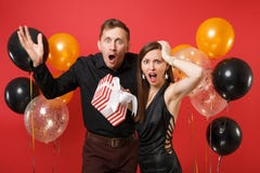 Les couples contrariés dans des vêtements noirs tiennent le boîte-cadeau célébrant la fête de vacances d'anniversaire d'isolement photo stock Les couples contrariés dans des vêtements noirs tiennent le boîte-cadeau célébrant la fête de vacances d'anniversaire d'isolement photo stock