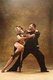 Les couples de salle de bal de danse en or habillent la danse sur le fond de studio image libre de droits Les couples de salle de bal de danse en or habillent la danse sur le fond de studio image libre de droits