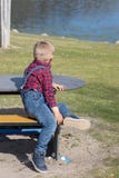 Les enfants s'asseyent sur un banc en bois en plein air photo stock Les enfants s'asseyent sur un banc en bois en plein air photo stock