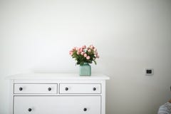 Les fleurs sur un coffre des tiroirs blanc, photographie stock Les fleurs sur un coffre des tiroirs blanc, photographie stock