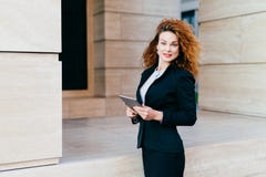 Les gens, affaires, concept moderne de technologie Jolie femme d'affaires utilisant la veste noire et la jupe se tenant près de s image stock Les gens, affaires, concept moderne de technologie Jolie femme d'affaires utilisant la veste noire et la jupe se tenant près de s image stock