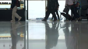 Les gens avec le bagage passant par la fenêtre dans l'aéroport Les gens avec le bagage passant par la fenêtre dans l'aéroport
