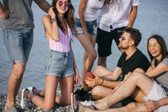 Les gens passant le temps gentil ensemble tout en se reposant sur la plage, ayant l'amusement et buvant de la bière images stock Les gens passant le temps gentil ensemble tout en se reposant sur la plage, ayant l'amusement et buvant de la bière images stock
