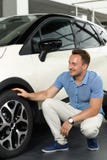 Les hommes s'asseyent près la voiture de toute neuve photographie stock libre de droits Les hommes s'asseyent près la voiture de toute neuve photographie stock libre de droits
