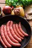 Les ingrédients pour préparer le repas, les saucisses crues crues en fer ont moulé la casserole, pommes de terre, oignon, ail, co Images stock Les ingrédients pour préparer le repas, les saucisses crues crues en fer ont moulé la casserole, pommes de terre, oignon, ail, co Images stock