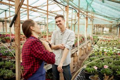 Les jardiniers de type et de fille dans des chapeaux de paille se tiennent en serre chaude un jour ensoleillé image libre de droits Les jardiniers de type et de fille dans des chapeaux de paille se tiennent en serre chaude un jour ensoleillé image libre de droits