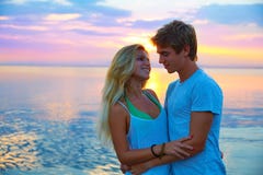Les jeunes couples blonds étreignent dans le lac de mer de coucher du soleil heureux image libre de droits Les jeunes couples blonds étreignent dans le lac de mer de coucher du soleil heureux image libre de droits