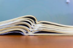 Les magazines ouvertes se trouvent sur l'un l'autre sur une table brune, documents sont en gros plan empilé image stock Les magazines ouvertes se trouvent sur l'un l'autre sur une table brune, documents sont en gros plan empilé image stock