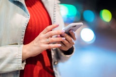 Les mains de la jeune femme à l'aide de son téléphone portable dans la nuit ont illuminé la rue Fille avec le smartphone Concept photographie stock libre de droits Les mains de la jeune femme à l'aide de son téléphone portable dans la nuit ont illuminé la rue Fille avec le smartphone Concept photographie stock libre de droits