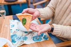 Les mains du ` s d'homme dans un chandail tiennent un morceau de pizza Plan rapproché images libres de droits Les mains du ` s d'homme dans un chandail tiennent un morceau de pizza Plan rapproché images libres de droits