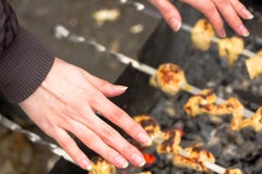 Les mains gelées de la fille au-dessus du gril avec le barbecue images stock Les mains gelées de la fille au-dessus du gril avec le barbecue images stock