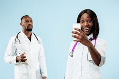 Les médecins afro-américains heureux féminins et masculins sur le fond bleu images stock Les médecins afro-américains heureux féminins et masculins sur le fond bleu images stock