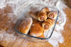 Les petits pains cuits au four frais avec la saucisse et les tartes se situent dans une glace sur une table en bois couverte de l photo libre de droits Les petits pains cuits au four frais avec la saucisse et les tartes se situent dans une glace sur une table en bois couverte de l photo libre de droits