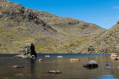 Les pierres ont dispersé dans une eau superficielle peu profonde dans le secteur de lac, R-U photos libres de droits Les pierres ont dispersé dans une eau superficielle peu profonde dans le secteur de lac, R-U photos libres de droits
