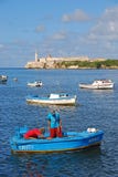 Les pêcheurs travaillant à un petit bateau bleu avec Morro se retranchent à l'arrière-plan image stock Les pêcheurs travaillant à un petit bateau bleu avec Morro se retranchent à l'arrière-plan image stock