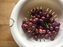 Les raisins pourpres ont tiré utilisant la lumière naturelle sur une table en bois image stock Les raisins pourpres ont tiré utilisant la lumière naturelle sur une table en bois image stock