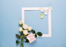 Les roses blanches et le présent blanc de cadre ont décoré des feuilles fraîches sur un fond bleu Disposition plate Copiez l'espa images libres de droits Les roses blanches et le présent blanc de cadre ont décoré des feuilles fraîches sur un fond bleu Disposition plate Copiez l'espa images libres de droits