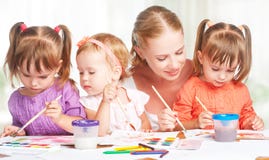 Les soeurs jumelles d'enfants dessinent des peintures avec sa mère dans le jardin d'enfants photos libres de droits Les soeurs jumelles d'enfants dessinent des peintures avec sa mère dans le jardin d'enfants photos libres de droits